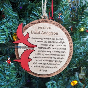 May include: A wooden Christmas ornament with a red cardinal design and a poem about remembering a loved one. The ornament reads "In loving memory 1913-1932 Bazil Anderson".
