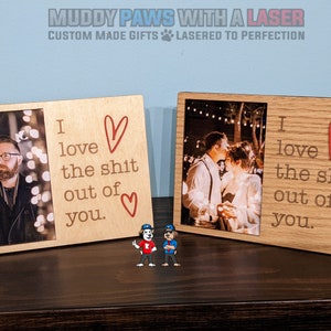 May include: Two wooden picture frames with a photo in each. The frames are brown and have a light wood grain. The text in the frames reads "I love the shit out of you." with a red heart symbol.