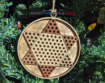 Puede incluir: Un adorno navideño de madera con forma de estrella con un patrón de tablero de ajedrez. El adorno está hecho de dos tipos diferentes de madera, una clara y otra oscura. El adorno está colgado de un árbol de Navidad.