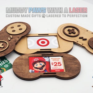 May include: Wooden gift card holder shaped like a video game controller. The holder has a slot for a gift card and is decorated with a brown and beige wood finish. The text "Nintendo eShop $25" is visible on the gift card.
