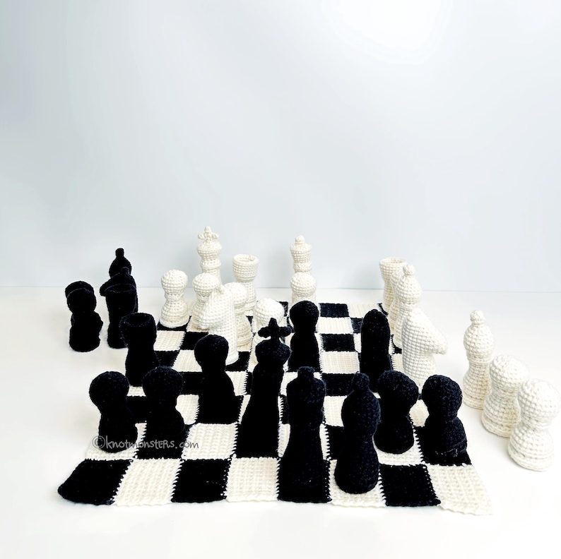May include: A crocheted chess set with black and white pieces arranged on a checkered board. The pieces are in the traditional chess shapes. The board is a black and white checkerboard pattern.
