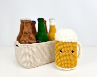 May include: A crocheted beer mug with a smiling face, next to a six-pack of crocheted beer bottles in a white crocheted carrier.