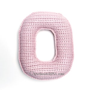 May include: A pink crocheted letter O. The letter is made with a single crochet stitch and has a slightly textured surface.