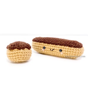 May include: Two crocheted eclairs, one large and one small, with chocolate icing and a smiling face. The larger eclair has a wink.