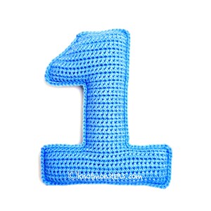 Peut inclure: Un chiffre un crocheté bleu clair, isolé sur fond blanc. Le chiffre est fait d'un fil texturé et a des bords arrondis. L'adresse du site Web "©knotmonsters.com" est visible au bas du chiffre.