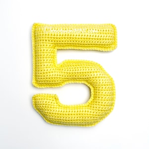 May include: A yellow crocheted number five. The number is made with a single crochet stitch and is a soft, plush toy.