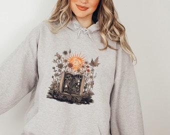 May include: Gray hooded sweatshirt with a graphic print of an open book with a sun and flowers. The book is surrounded by flowers and leaves.
