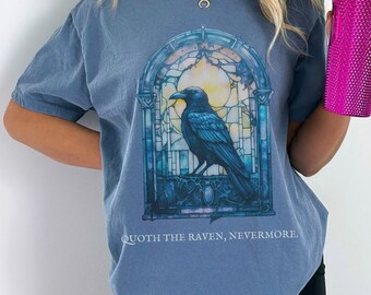 May include: A blue t-shirt with a stained glass design featuring a raven and the text "Quoth the Raven, Nevermore."