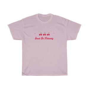 May include: A light pink t-shirt with a graphic of four red cherries and the text "Smash The Patriarchy" in pink.