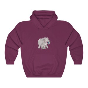 Op de afbeelding: Een maroon hoodie met een afbeelding van twee olifanten, waarvan er &eacute;&eacute;n een wereldbol vasthoudt met de tekst "Love each other, Love the Earth".