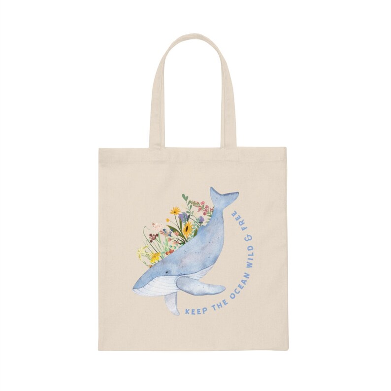 May include: A beige tote bag featuring a blue whale illustration with colourful flowers. The text "Keep the ocean wild & free" is printed on the bag.
