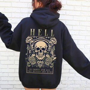 Puede incluir: Sudadera con capucha negra con un estampado gráfico de una calavera con rosas y el texto "HELL IS EMPTY AND ALL THE DEVILS ARE HERE".