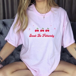May include: Pink oversized t-shirt with a graphic of three red cherries and the text "Smash The Patriarchy" in red.