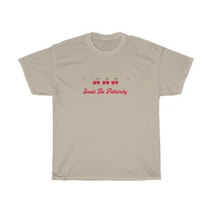 May include: A light beige t-shirt with a pink graphic of cherries and the text "Smash The Patriarchy".