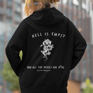 Puede incluir: Sudadera con capucha negra con un estampado gráfico blanco de una rosa con una serpiente enroscada a su alrededor. El texto "El infierno está vacío y todos los demonios están aquí" está impreso debajo del gráfico. La cita se atribuye a William Shakespeare.