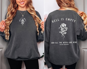 May include: A dark gray sweatshirt with a white graphic print on the front and back. The front print says "Hell is Empty" with a rose and snake design. The back print says "Hell is Empty and all the devils are here" with a rose and snake design and the text "William Shakespeare".