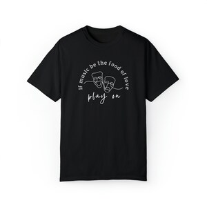 May include: Black t-shirt with a white graphic design featuring two theatre masks and the text "If music be the food of love play on."