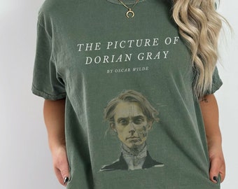 May include: A green t-shirt with a vintage look featuring a graphic of a man's face and the text "THE PICTURE OF DORIAN GRAY BY OSCAR WILDE".