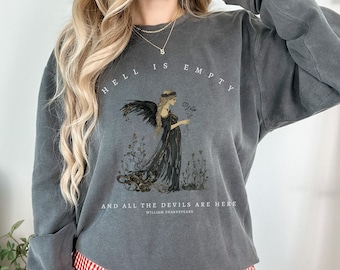 Op de afbeelding: Grijs sweatshirt met een afbeelding van een vrouw met vleugels en de tekst "De hel is leeg en alle duivels zijn hier" van William Shakespeare.