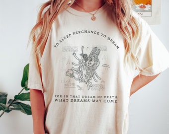 May include: A cream-colored t-shirt with a black graphic of a fairy with wings and the text "To sleep perchance to dream" and "For in that dream of death what dreams may come".