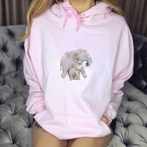 Op de afbeelding: Roze hoodie met een afbeelding van twee olifanten en de tekst "Love each other Love the Earth".