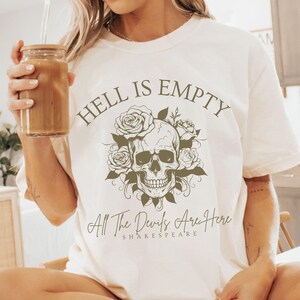 May include: White t-shirt with a skull and roses graphic and the text "Hell is Empty All The Devils Are Here Shakespeare".