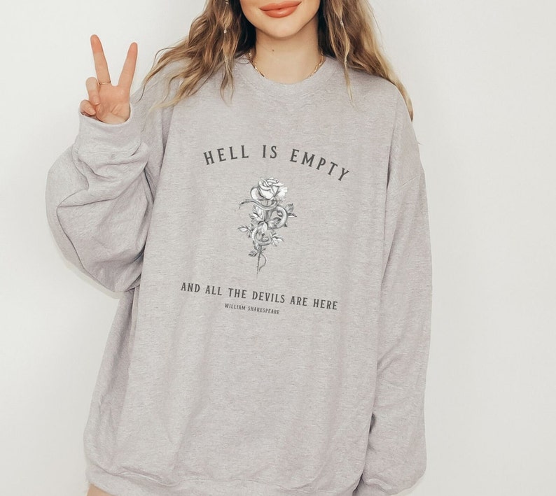 Puede incluir: Sudadera gris con el texto "El infierno est&aacute; vac&iacute;o y todos los demonios est&aacute;n aqu&iacute;" con un gr&aacute;fico de rosa y serpiente en blanco y negro. El texto "William Shakespeare" est&aacute; debajo del gr&aacute;fico.