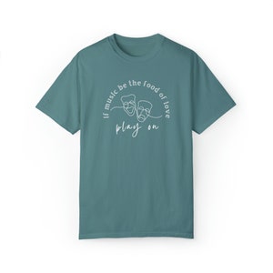 May include: Teal blue t-shirt with a white graphic design of two theatre masks and the text "If music be the food of love play on."