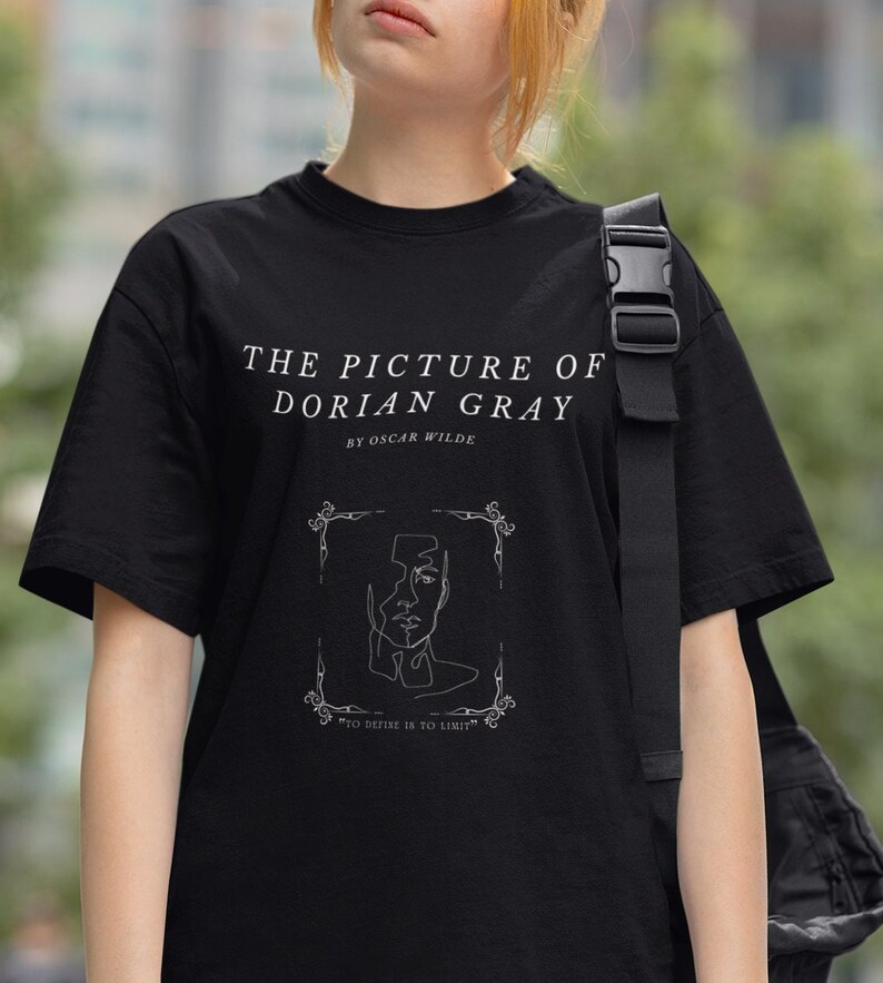 May include: Black t-shirt with a white graphic design featuring a line drawing of a face with the text "THE PICTURE OF DORIAN GRAY BY OSCAR WILDE" and "TO DEFIKE IS TO LIMIT".