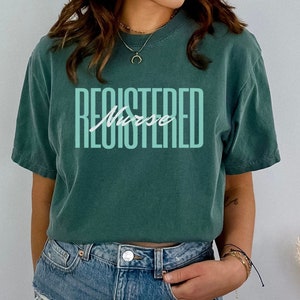 May include: A teal blue t-shirt with the text "REGISTERED Nurse" in a light green color.