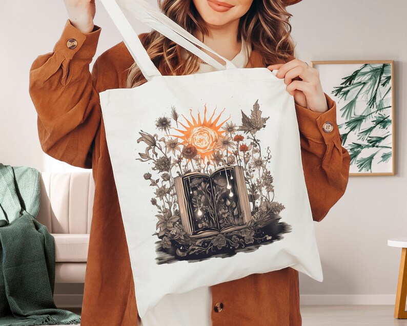May include: A white canvas tote bag with a colorful illustration of a book surrounded by flowers and a sun. The book is open and has a glowing light emanating from it.