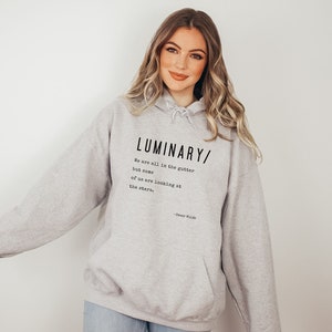 May include: A gray hooded sweatshirt with the text "LUMINARY/ We are all in the gutter but some of us are looking at the stars."  - Oscar Wilde