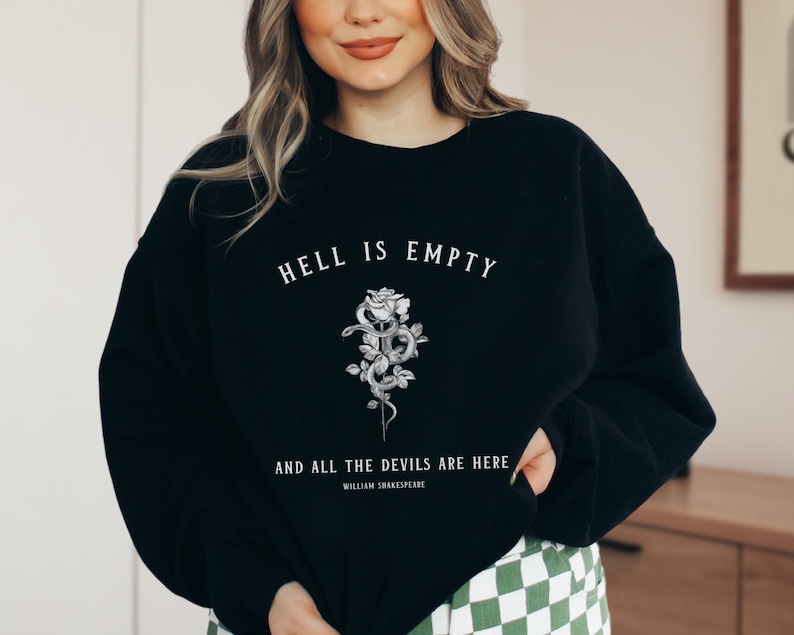 Puede incluir: Sudadera negra con un estampado gr&aacute;fico blanco de una rosa y una serpiente con el texto "El infierno est&aacute; vac&iacute;o y todos los demonios est&aacute;n aqu&iacute;" y "William Shakespeare" debajo.