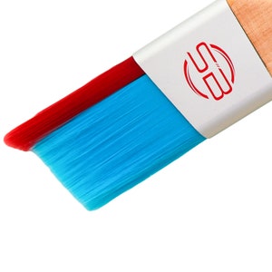 Op de afbeelding: Een close-up van een blauwe en rode verfkwast met een witte handvat. Het handvat heeft een rode cirkel met de letter "H" erin.