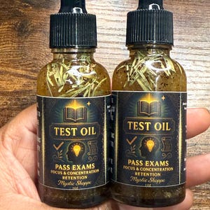 May include: Two glass bottles of "Test Oil" with black droppers. The labels read "Pass Exams, Focus & Concentration, Retention" and "Mystic Shoppe". The bottles contain herbs and a golden-brown liquid.