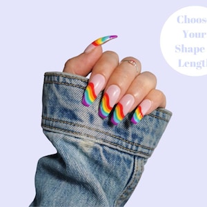 Peut inclure: Des ongles en forme d'amande avec un dégradé arc-en-ciel sur une base blanche, présentés sur une main portant une veste en jean. Le texte "Choose Your Shape & Length" est dans un cercle blanc sur un fond violet clair.