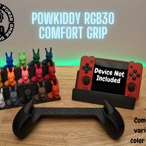 Pode incluir: Um console de jogos portátil preto com uma carcaça vermelha e o texto "Device Not Included" na tela. O console está sentado em um suporte preto. Um aperto ergonômico preto para o console está em primeiro plano. O aperto está etiquetado como "RGB30". Uma variedade de figuras impressas em 3D coloridas estão no fundo.