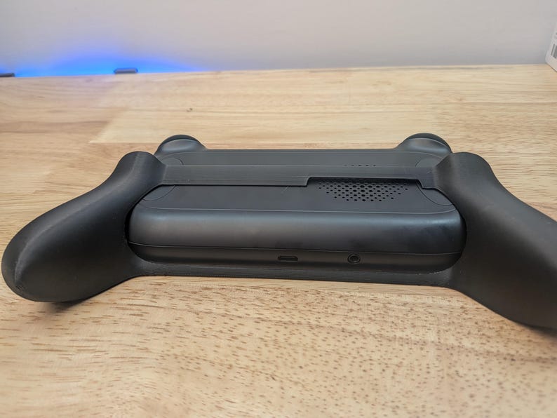 Puede incluir: Consola de juegos port&aacute;til negra con agarre texturizado y altavoz integrado. La consola tiene un puerto USB-C y una toma de auriculares.