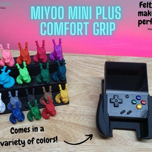 Puede incluir: Una empuñadura impresa en 3D para la consola de juegos portátil Miyoo Mini Plus. La empuñadura está disponible en una variedad de colores y cuenta con tiras de fieltro para un ajuste seguro. El texto "MIYOO MINI PLUS COMFORT GRIP" se muestra en letras azules grandes. El texto "Felt strips make for a perfect fit" se muestra en letras negras. El texto "THANK YOU" se muestra en letras negras pequeñas.