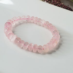 May include: A pink rose quartz beaded bracelet with a stretchy elastic band.