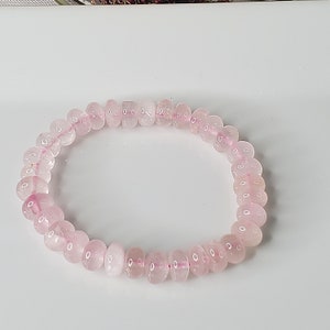 May include: A pink rose quartz beaded bracelet. The beads are round and smooth, and the bracelet is made with elastic.