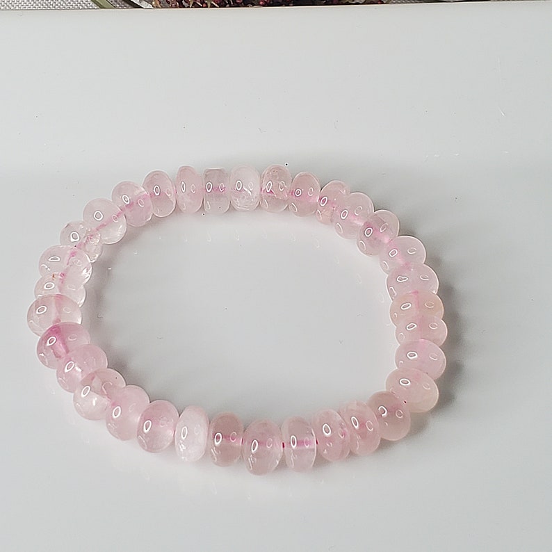May include: A pink rose quartz beaded bracelet. The beads are round and smooth, and the bracelet is made with elastic.