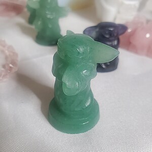 May include: A green jade figurine of a popular fictional character. The figurine is standing on a round base.