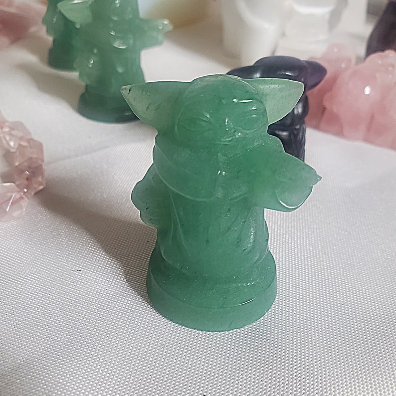 May include: A green figurine of a character from the Star Wars franchise. The figurine is made of a translucent material and has a detailed design.