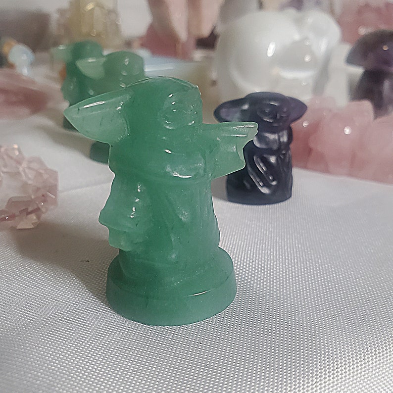 May include: A green figurine of a popular character from the Star Wars franchise. The figurine is made of a smooth, polished material and has a detailed design.