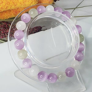 May include: A bracelet made of purple, white, and green gemstone beads. The beads are round and have a smooth, polished finish.