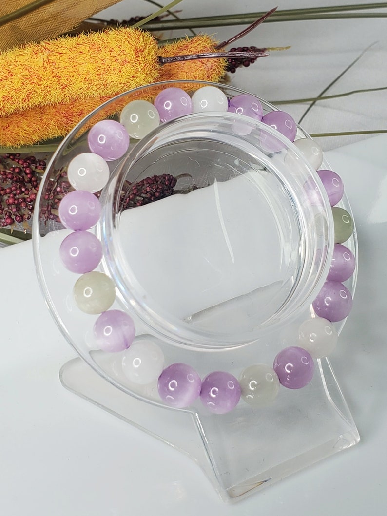 May include: A bracelet made of purple, white, and green gemstone beads. The beads are round and have a smooth, polished finish.