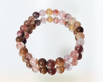 May include: A double-strand bracelet made of round, multi-colored gemstone beads. The beads are a mix of brown, pink, and clear quartz.