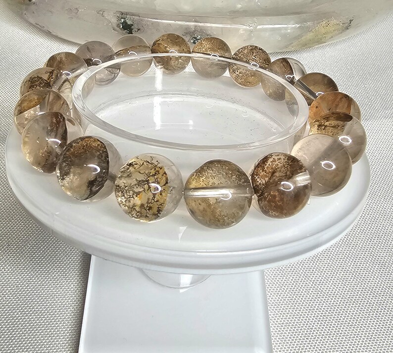 May include: A bracelet made of brown and clear crystal beads with a cloudy, speckled appearance. The beads are round and have a smooth, polished finish.