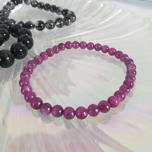 May include: A pink gemstone bracelet with small, round beads. The bracelet is made of natural stones and is a beautiful shade of pink.